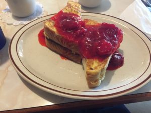 A plate of french toast topped with strawberries