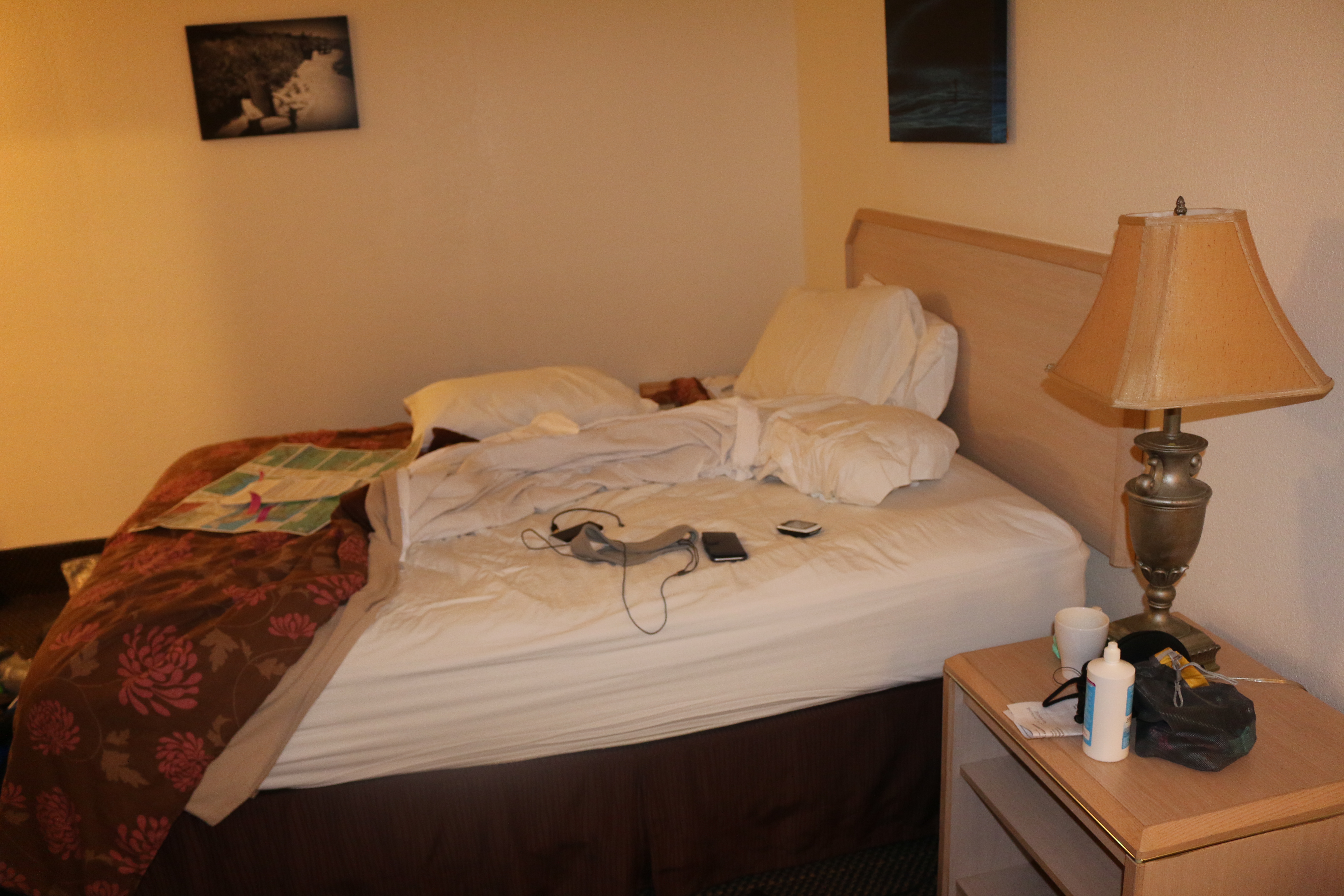 A hotel room bed, unmade and cluttered.