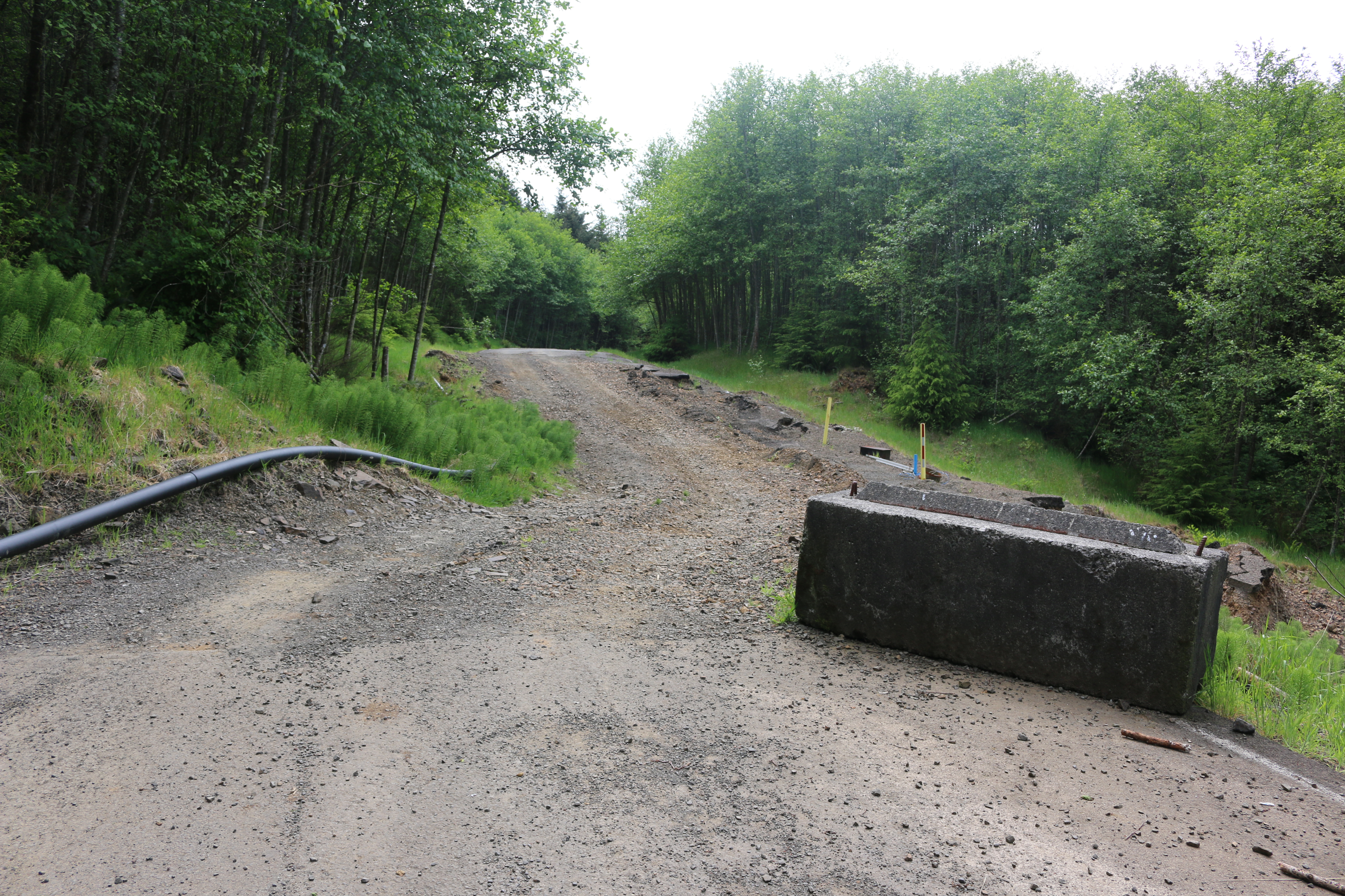 A road made impassable to cars by a landslide. The expanse is uneven and gravelly, but walkable.