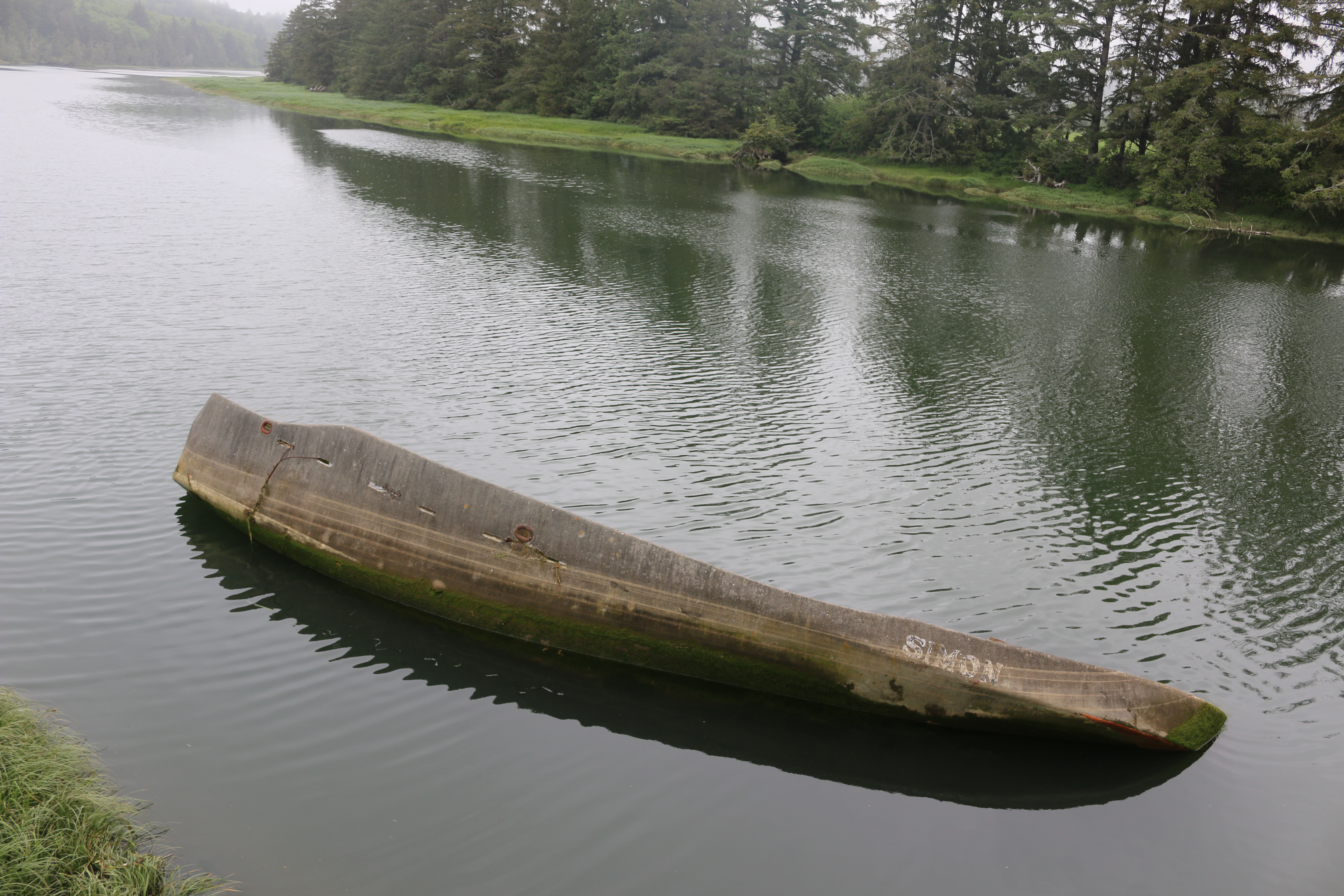 A capsized boat in the river. The boat is named Simon