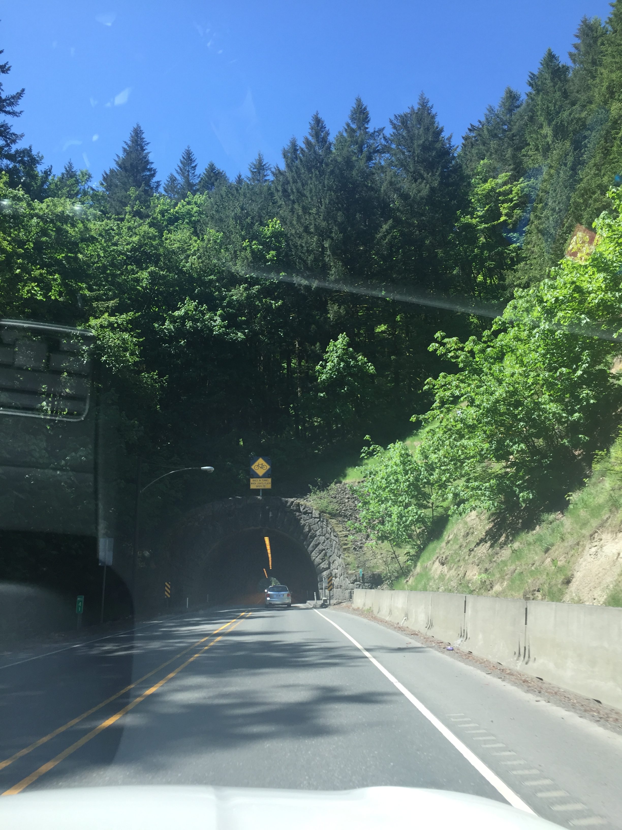 a tunnel on a road with a warning sign saying that lights flash in the tunnel when a cyclist is present.